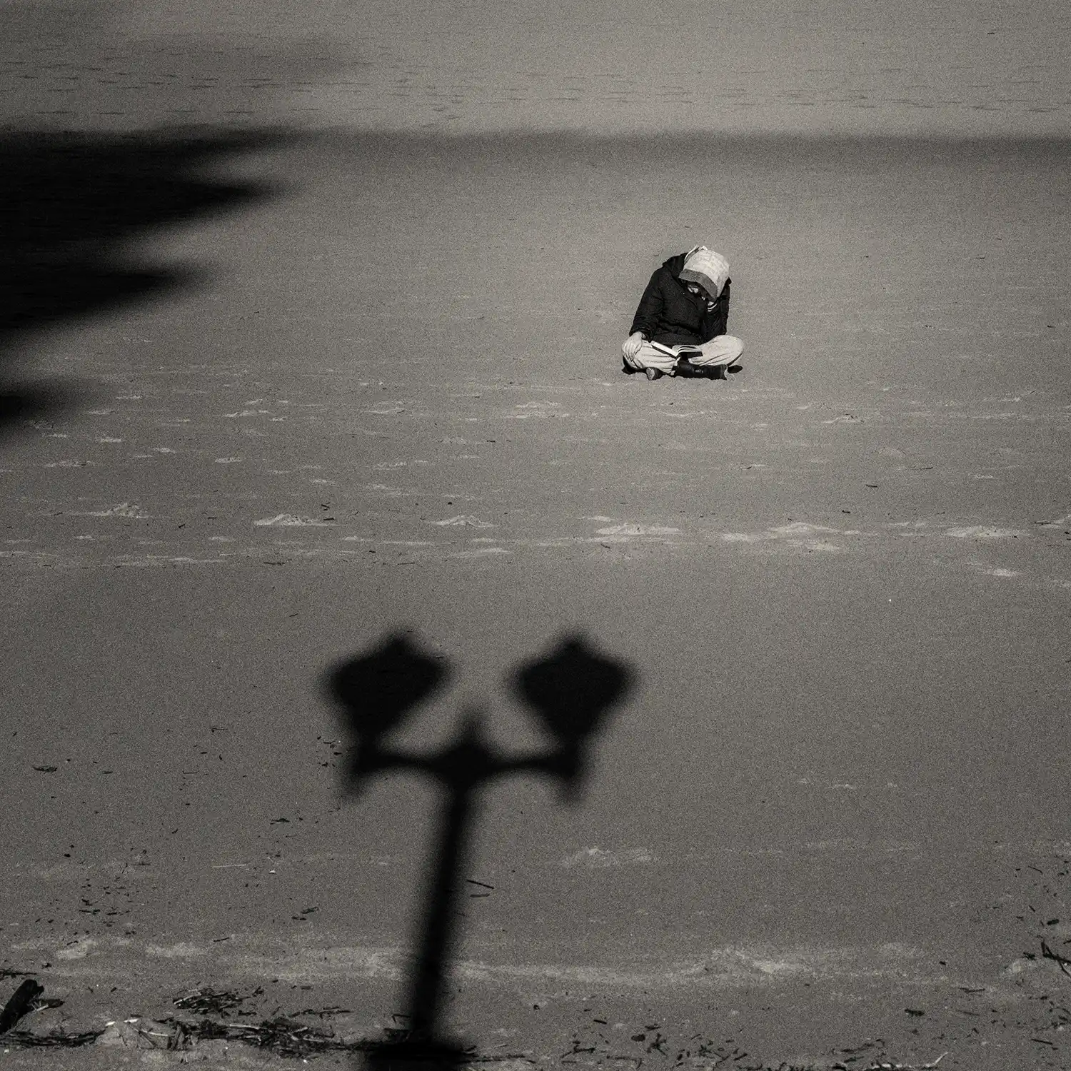 mujer leyendo en la arena en actitud introspectiva frente al mar