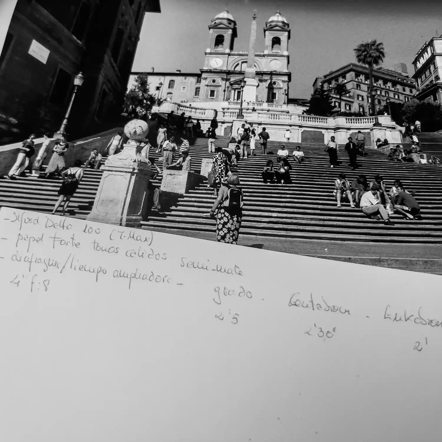 Fotografía en blanco y negro junto a una hoja con anotaciones del proceso de revelado, incluyendo tiempos, revelador y película