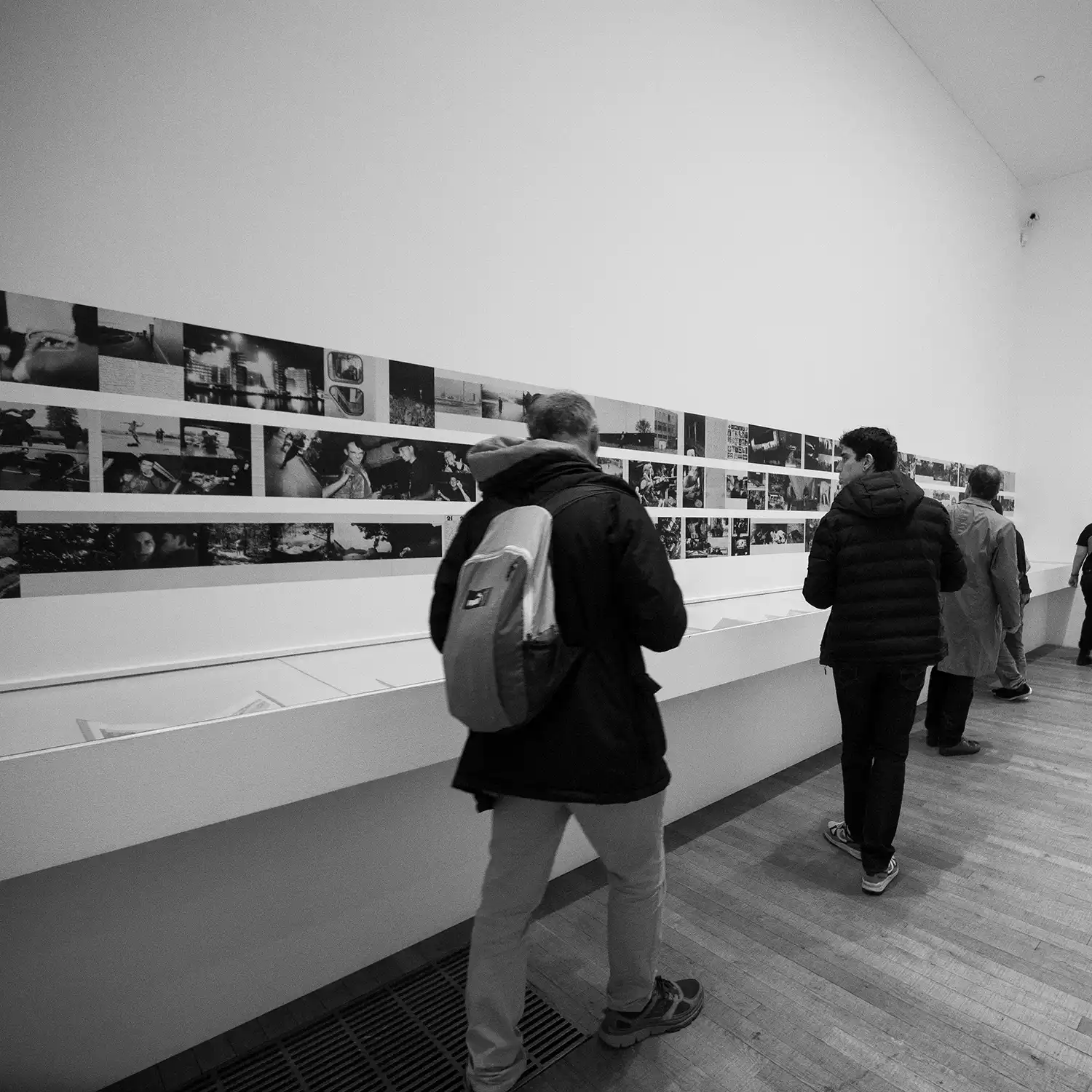 Personas recorriendo una exposición de fotografía en una sala de galería